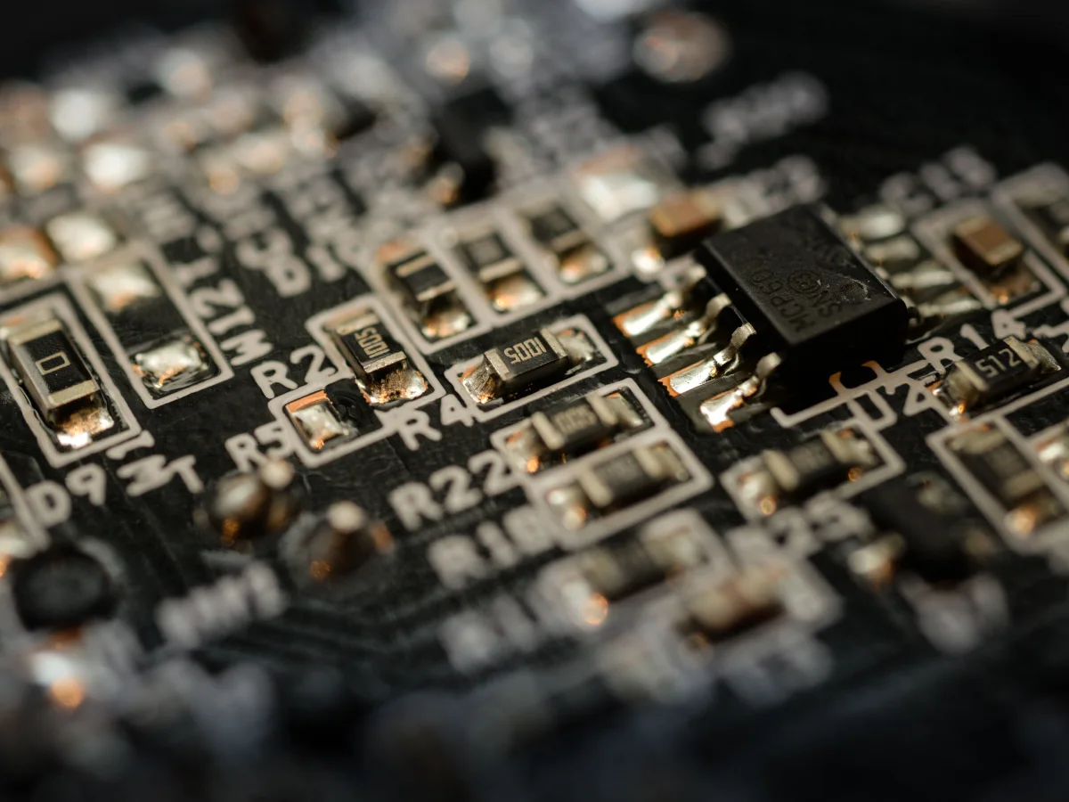 An integrated circuit, SMD resistors and solder joints on a black circuit board